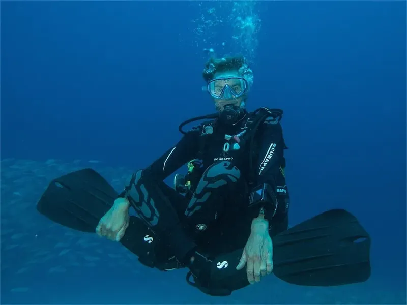 Plongeur en combinaison noire équipé nageant dans une eau bleue