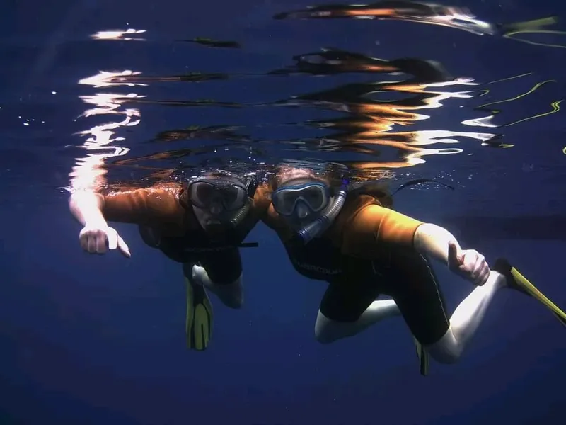 Deux plongeurs en apnée nagent face à la caméra dans l'eau bleue