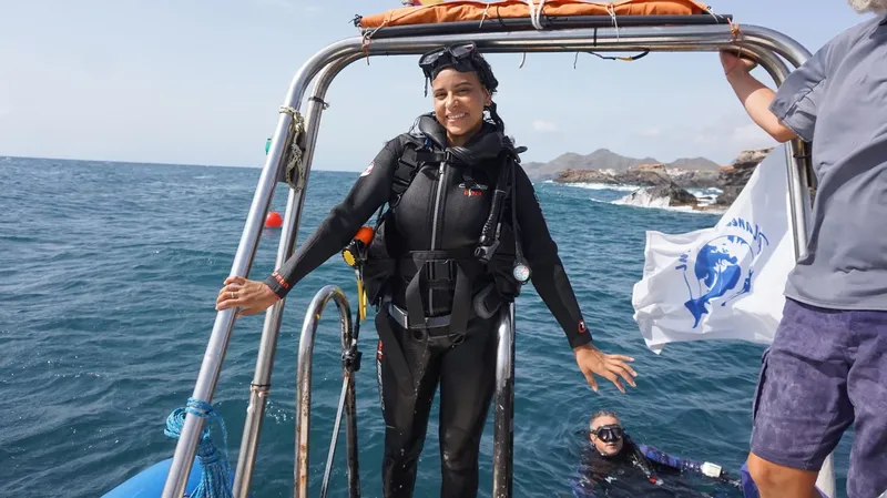 Plongeuse souriante sur un bateau, prête à plonger en mer