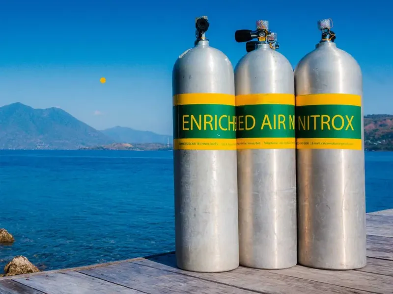 Trois bouteilles de plongée Nitrox alignées sur un ponton en bois