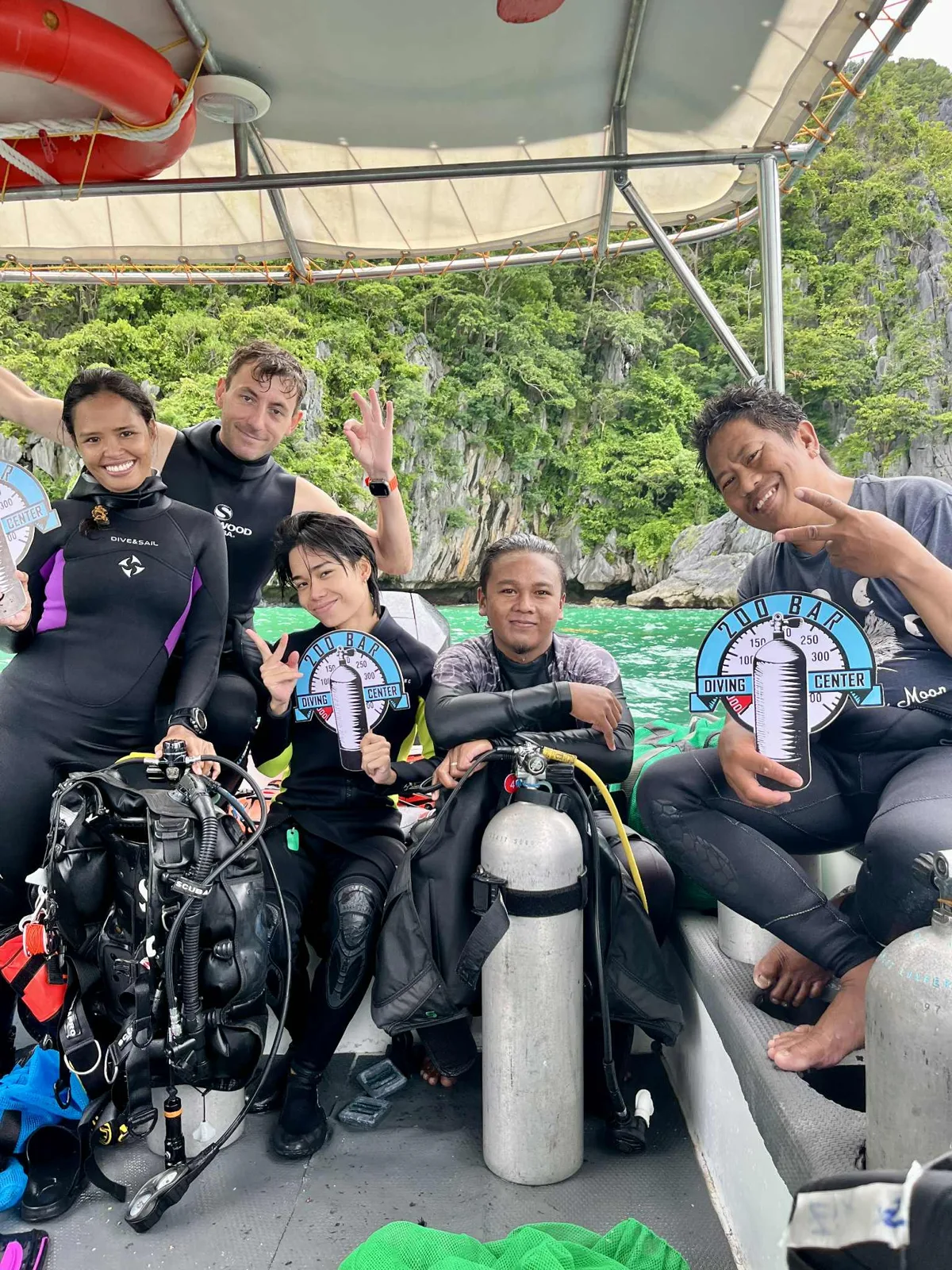 Groupe de plongeurs souriants sur un bateau, équipés et prêts
