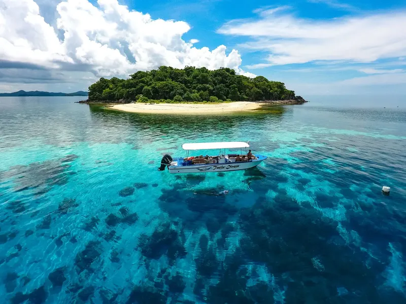 Bateau de plongée naviguant vers une île tropicale ensoleillée