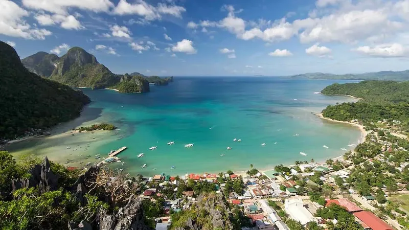 Vue aérienne d'une baie turquoise avec des bateaux et une ville côtière