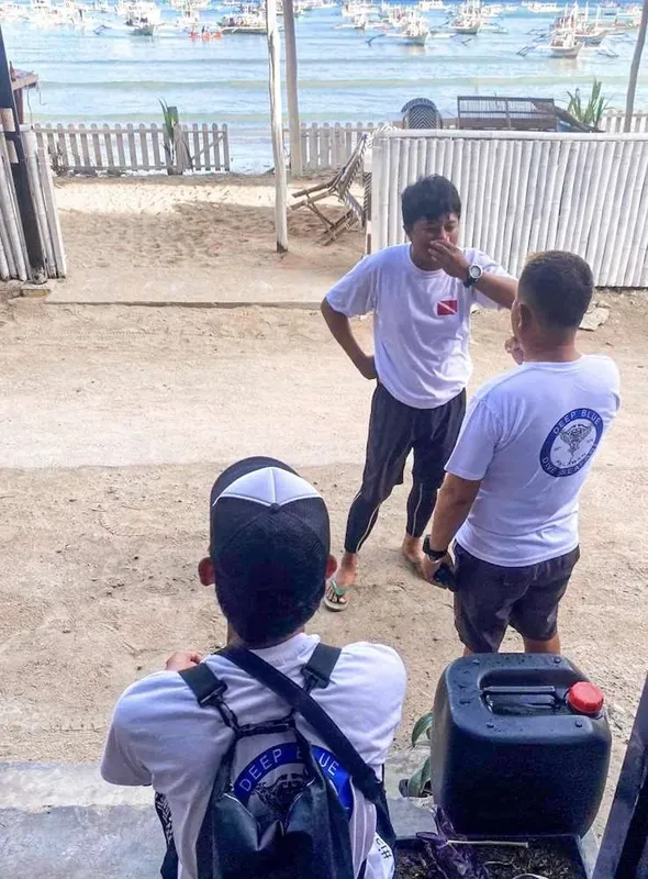 Trois hommes discutent sur une plage, un instructeur explique un plan
