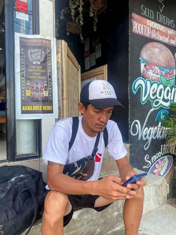 Un homme regarde son téléphone devant une façade colorée et animée