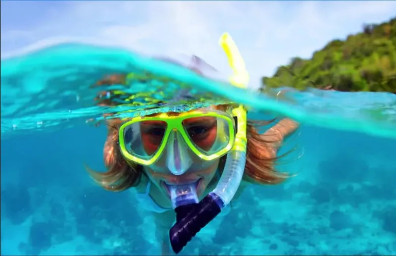 Snorkeleur souriant avec masque et tuba dans une eau turquoise claire