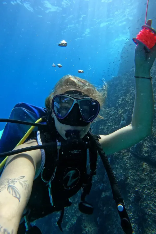 Plongeuse souriante avec masque et détendeur, explorant les fonds marins