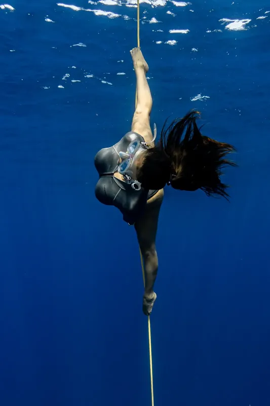 Apnée : une plongeuse descend le long d'un câble dans l'eau bleue