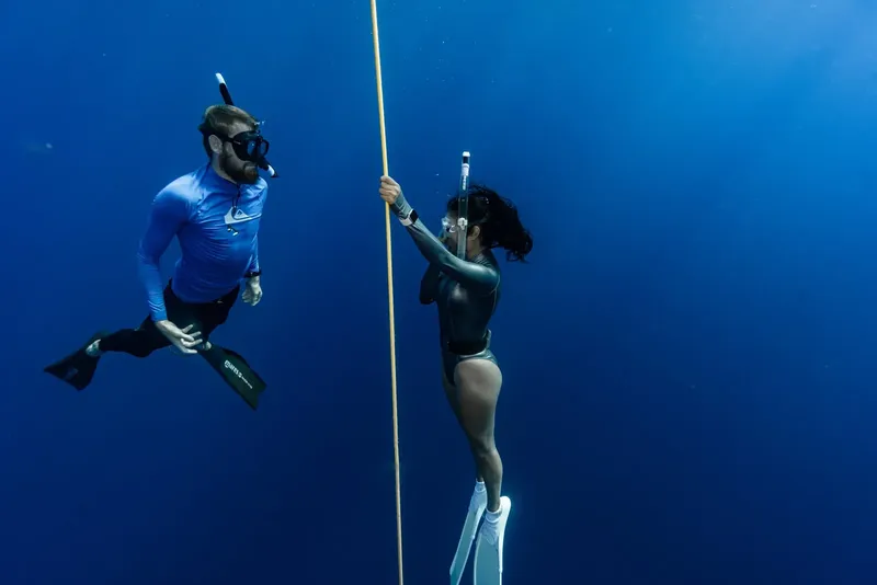 Deux apnéistes évoluent dans l'eau bleue, un homme et une femme