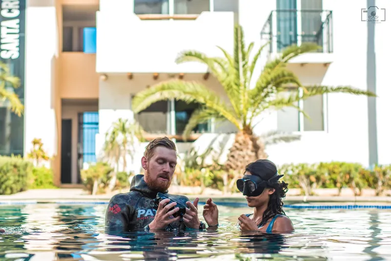 Deux personnes dans une piscine, discutent et regardent un objet