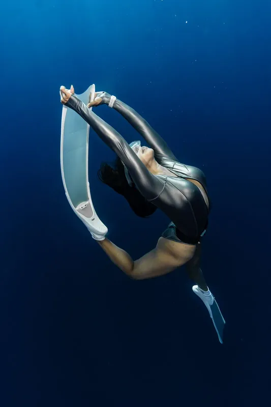 Apnée : une plongeuse en équilibre vertical dans l'eau bleue