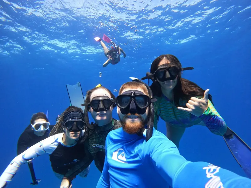 Groupe de plongeurs souriants avec masques et palmes dans l'eau bleue