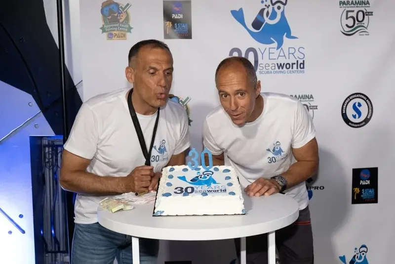 Deux hommes souriants devant un gâteau d'anniversaire avec des billets