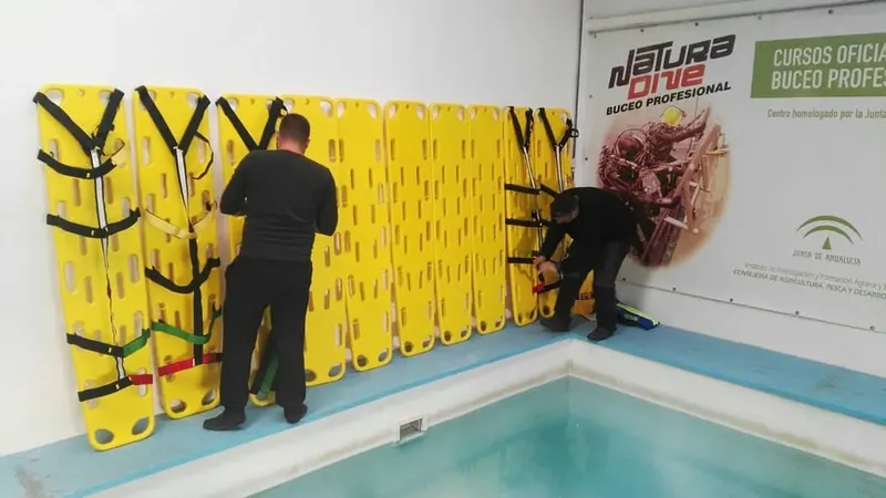 Deux personnes manipulent du matériel de plongée devant un mur avec une affiche