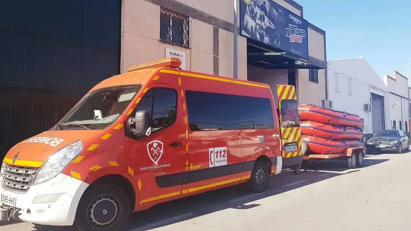 Véhicule orange remorquant des kayaks devant un bâtiment industriel