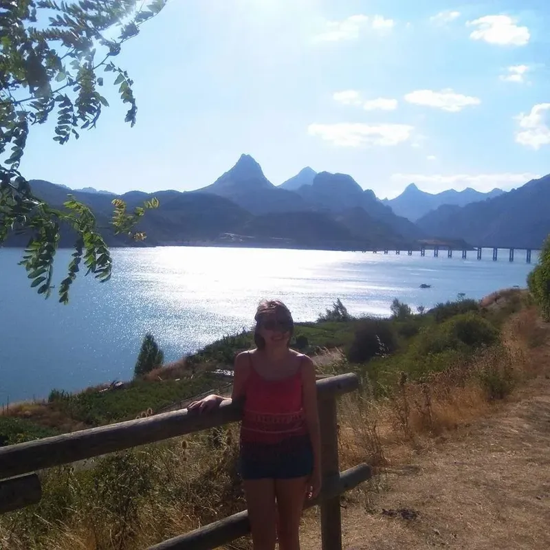 Jeune femme souriante se tenant devant un paysage marin montagneux