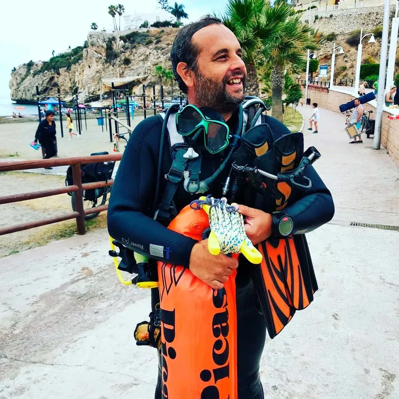 Plongeur souriant portant son équipement sur une promenade ensoleillée