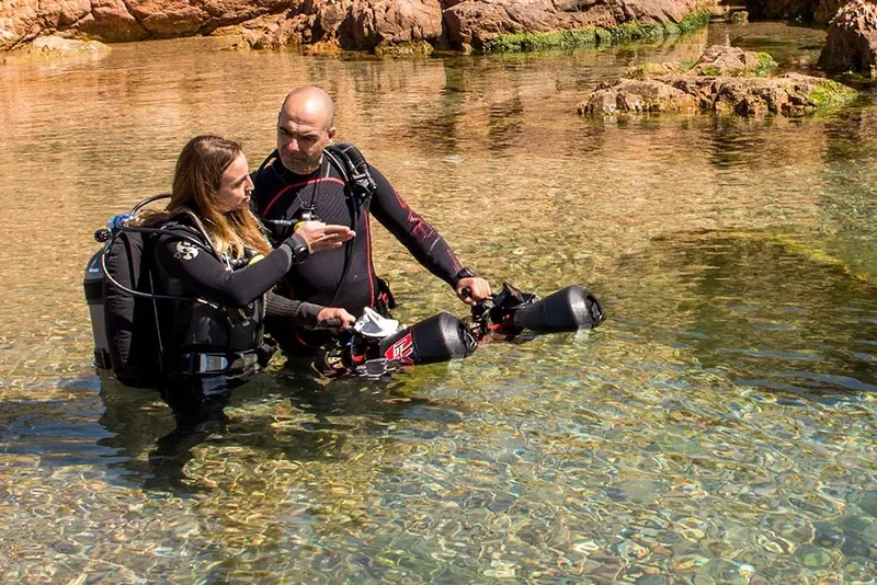 Deux plongeurs en combinaison se préparent dans une eau claire