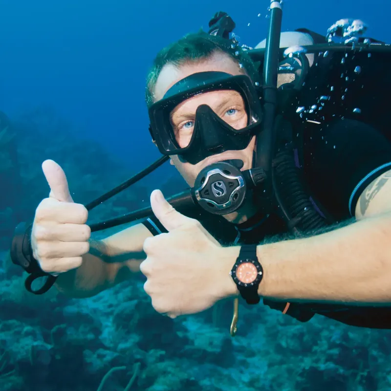 Plongeur souriant avec les pouces levés sous l'eau en pleine immersion