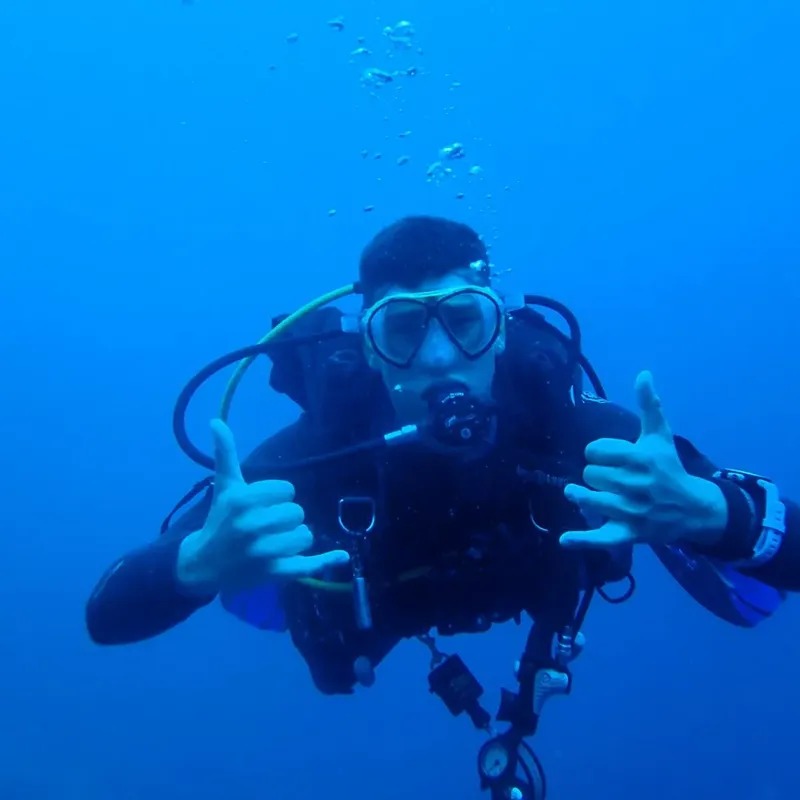 Plongeur souriant avec signe 'ok' des mains sous l'eau bleue