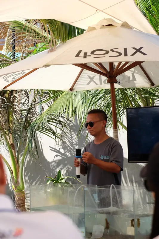 Homme parlant à un micro devant un parasol et un écran