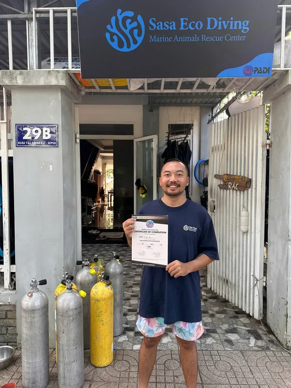 Un plongeur tient un certificat de completion devant le centre de plongée