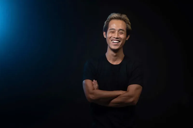Jeune homme souriant, les bras croisés, regardant vers la caméra