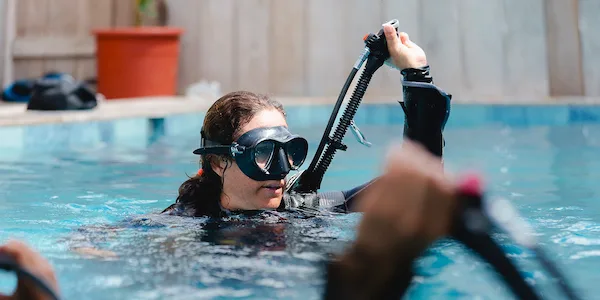 Une plongeuse s'entraîne avec son équipement dans une piscine bleue