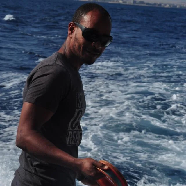 Homme souriant sur un bateau, tenant un masque de plongée