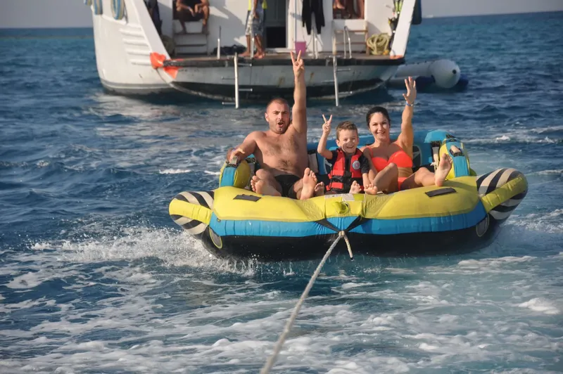 Famille s'amusant sur un bouée tractée par un bateau en mer