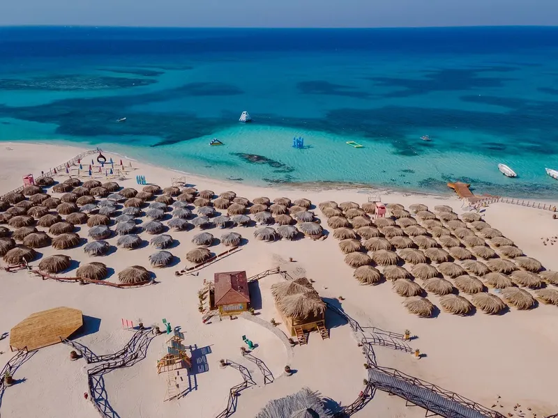Vue aérienne d'une plage avec des parasols et bateaux en mer