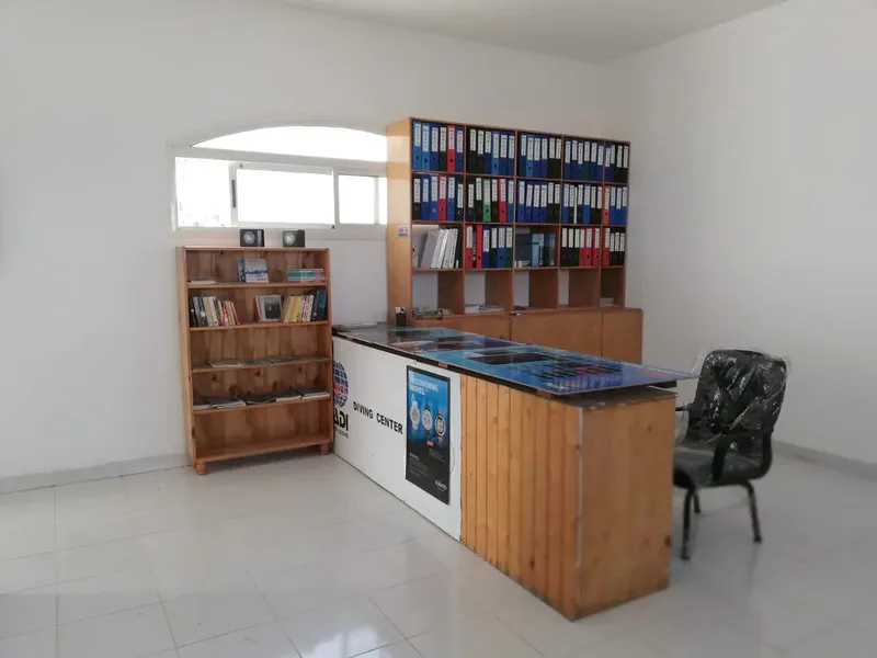 Bureau d'accueil avec étagères, comptoir et chaises dans un centre