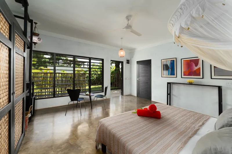 Chambre lumineuse avec lit à baldaquin et vue sur végétation tropicale