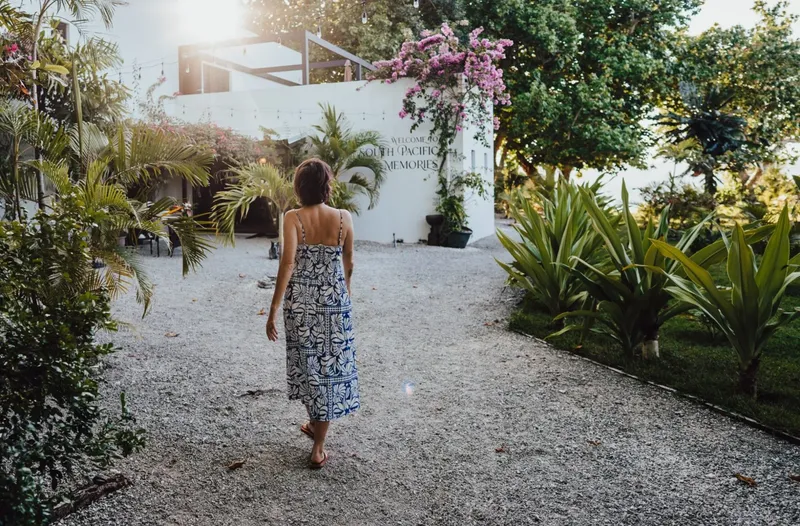 Femme marchant sur un chemin de gravier dans un jardin tropical