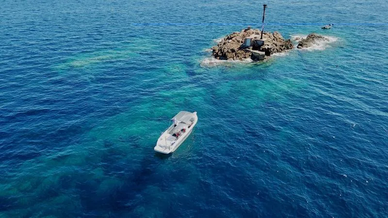 Bateau de plongée en mer, approche d'un petit îlot rocheux