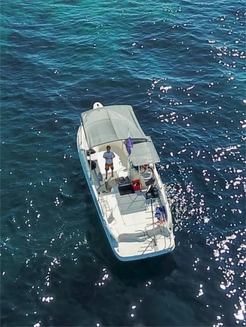 Homme debout sur un bateau blanc en mer, vue aérienne