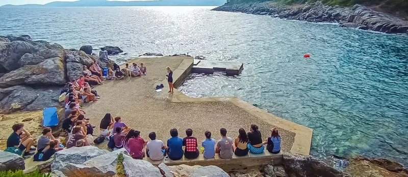Groupe de personnes assis sur un quai, un instructeur explique