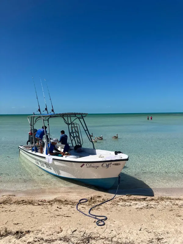 Bateau de pêche avec des personnes à bord sur une plage ensoleillée