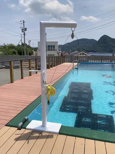 Piscine de formation avec treuil, terrasse en bois et bâtiments en arrière-plan