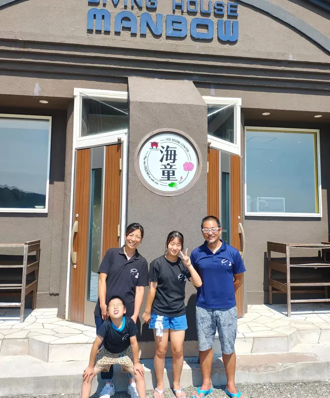 Quatre personnes souriantes posent devant l'entrée d'un centre de plongée