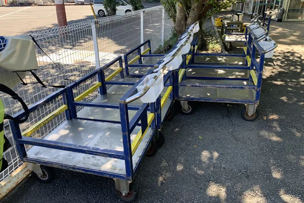 Chariots métalliques bleus et jaunes sur un sol gravillonné en extérieur