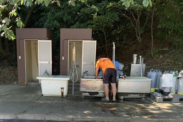 Personne nettoyant du matériel de plongée près de bacs de rinçage extérieurs