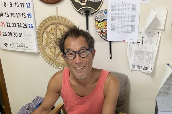 Un homme souriant avec des lunettes, assis dans un bureau décoré