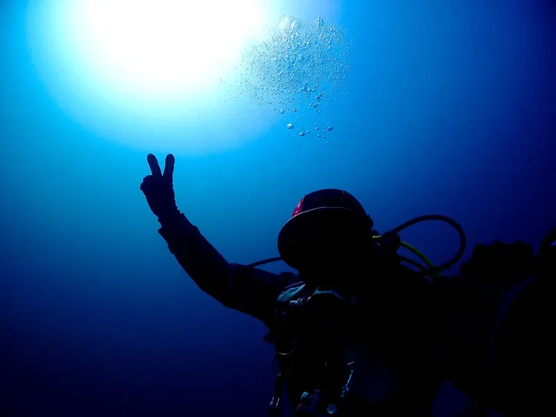 Plongeur silhouette sombre faisant un signe de la main sous l'eau