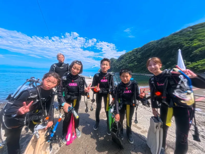 Groupe de plongeurs souriants équipés près de la mer ensoleillée