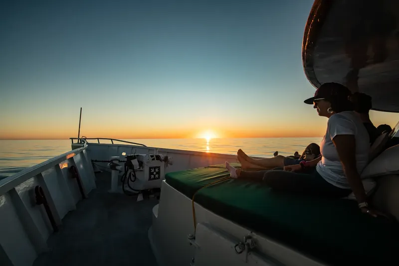 Deux personnes se reposent sur un bateau au coucher du soleil