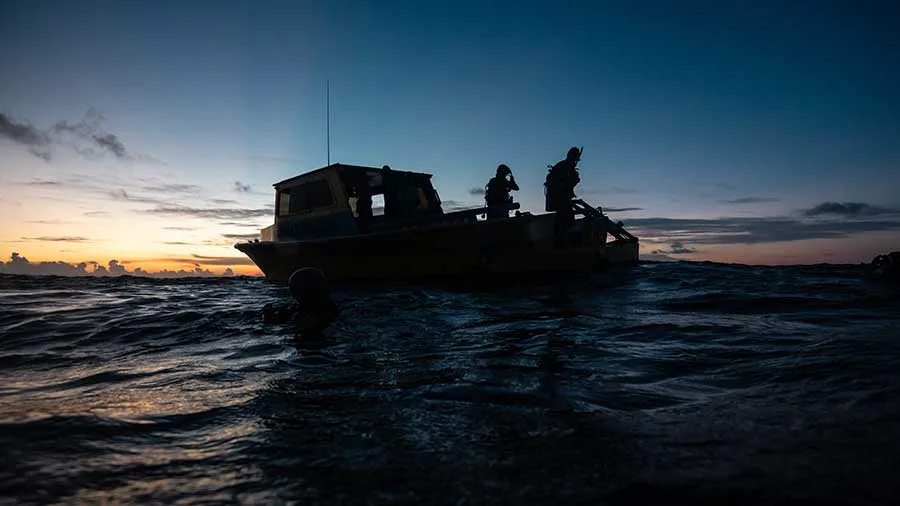 Silhouette de personnes à bord d'un bateau sur l'eau au coucher du soleil