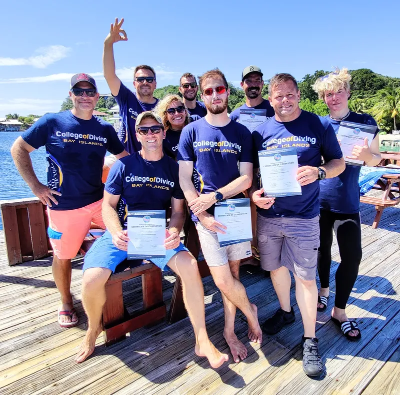 Groupe de plongeurs souriants sur un ponton avec des certificats