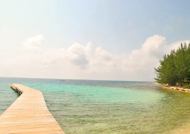 Un ponton en bois s'avance sur une mer turquoise et calme