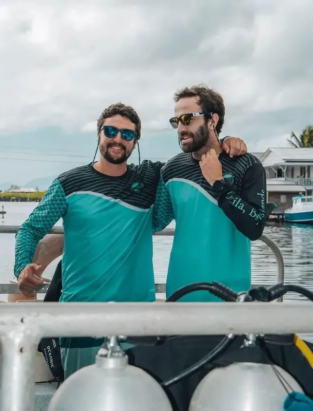 Deux plongeurs souriants se tiennent sur un bateau avec du matériel